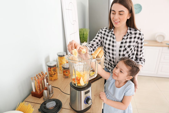 Mother And Little Daughter Making Healthy Smoothie In Kitchen