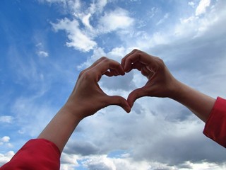 heart shape with human hands on sky and nature background