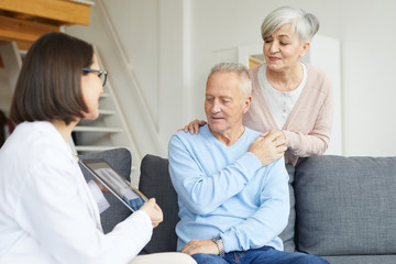 Obraz premium Portrait of modern senior couple listening to female doctor and looking at lung x-ray image during consultation in clinic