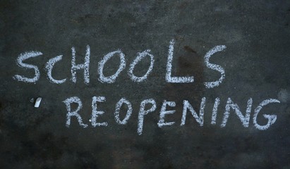 Fototapeta premium Schools Reopening Written with White Chalk on Black Surface