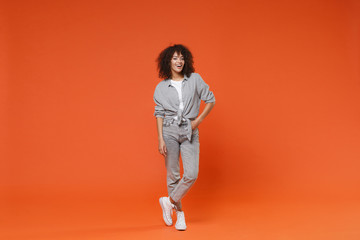 Fototapeta na wymiar Cheerful young african american woman girl in gray casual clothes posing isolated on orange background studio portrait. People sincere emotions lifestyle concept. Mock up copy space. Looking camera.