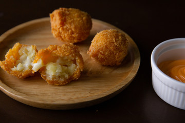 Cheese ball on a wooden plate on a black background