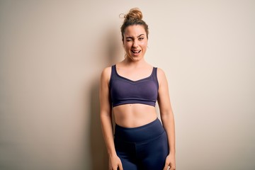 Young beautiful blonde sportswoman doing sport wearing sportswear over white background winking...