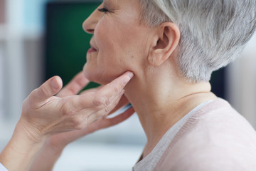 Close up of unrecognizable female doctor examining smiling senior woman during consultation in...