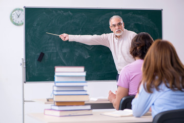 Old chemist teacher and two students in the classroom