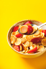Pancakes cereal quarantine trendy breakfast with strawberry on yellow background.