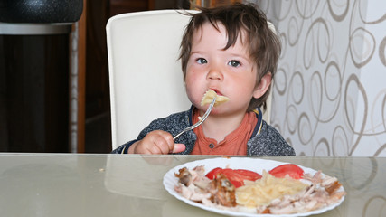child eating pasta at the table with a fork