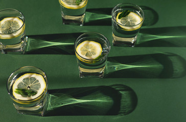 Glasses of fresh water with lemon and mint on green bacground. Selective focus