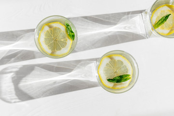 Top view of glasses with fresh lemonade on white wooden background. Refreshing and tonic drink