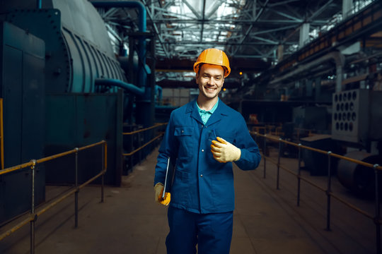 Smiling worker holds notebook, factory floor