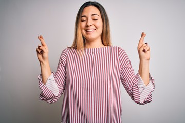 Young beautiful blonde woman with blue eyes wearing stiped t-shirt over white background gesturing...