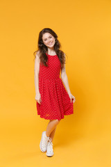 Smiling pretty young brunette woman girl in red summer dress posing isolated on yellow wall background studio portrait. People sincere emotions lifestyle concept. Mock up copy space. Looking camera.
