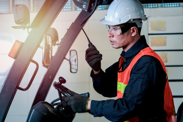Industrial engineer worker wearing helmetand safe glasses, holding radio walkie talkie, driving...