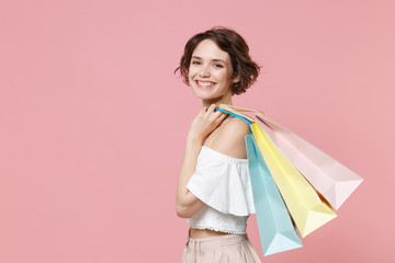 Side view of smiling young woman girl in summer clothes hold package bag with purchases isolated on pink background studio portrait. Shopping discount sale concept. Mock up copy space. Looking camera.