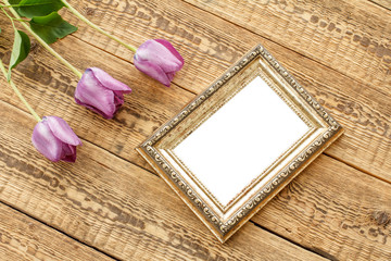 Vintage photo frame with tulips on wooden background.