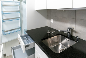 interior view of simple and modern kitchen in gray and white with black stone work top