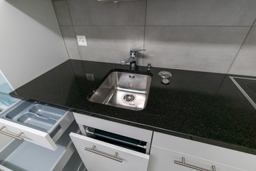 interior view of simple and modern kitchen in gray and white with black stone work top