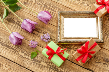 Vintage photo frame with tulips on wooden background.