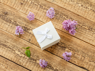 Gift box and lilac flowers on wooden boards.