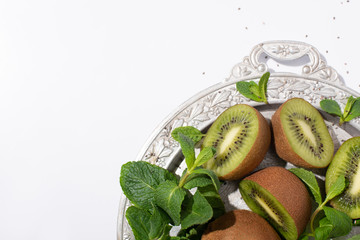 Fototapeta na wymiar top view of juicy kiwi fruits near fresh peppermint on silver plate isolated on white