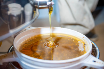 Dripping honey from honey extractor. Filtrating fresh honey through strainer