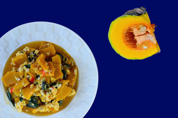 Stir fried pumpkin with egg and basil isolated on blue background.
