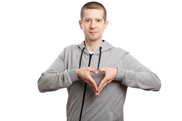 healthy, sporty man flirts, shows a gesture of heart and love. Dressed in a grey hooded jacket. A...