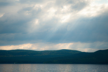 beautiful cloudy sky with sunbeams in the background mountains