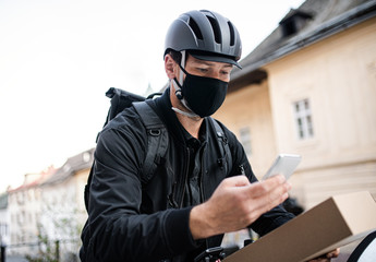 Delivery man courier with face mask and smartphone delivering in town.