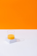 fresh orange juice in glass on white surface isolated on orange