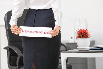 Young businesswoman with hemorrhoids in office