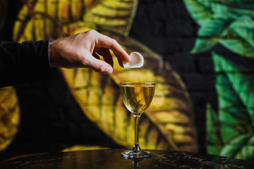Putting rose petal garnish on a nick and nora cocktail glass with a drink