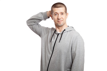 Obraz premium thoughtful, hesitant insecure male athlete makes a decision, hand by head. Dressed in a grey hooded jacket. looks in up. Isolated
