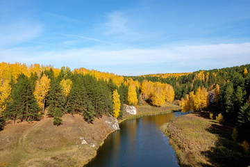 Autumn landscape in a mixed forest through which the river flows from above