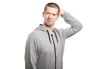 Fototapeta premium thoughtful, hesitant insecure male athlete makes a decision, hand by head. Dressed in a grey hooded jacket. looks in up. Isolated