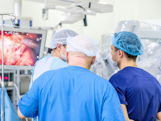 Obraz premium A group of surgeons in a medical uniform oversees medical equipment. The process of performing a surgical operation using a modern robotic surgical system.