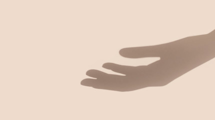 Hand shadow on nude beige background with copy space. Helping or begging hand