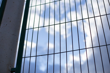 Trellised fence. Blue sky with clouds behind the fence. Conclusion concept, migration. Copy space