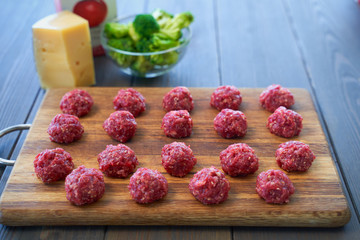 raw meatballs on a chopping board and ingredients. view from above. macro.