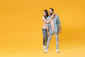 Cheerful young couple two friends guy girl in pastel blue casual clothes posing isolated on yellow...