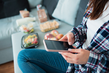 Food delivery concept. A young woman orders food using a smartphone at home.