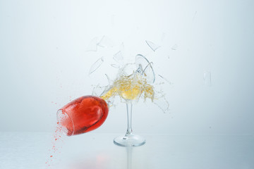Red and white wine glasses flying, colliding and crushing on white background. Splashes. Broken...