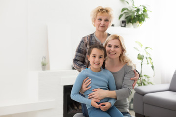 Fototapeta na wymiar Portrait of three generations of women look at camera posing for family picture, cute little girl hug mom and granny enjoy time at home, smiling mother, daughter and grandmother spend weekend together
