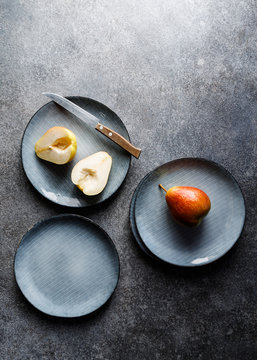 Blue food ceramic set with plates and pears over grey textured background. Minimalist style, top view.