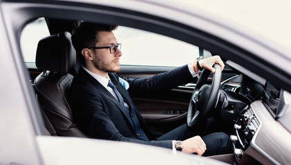 Young businessman driving alone in his new car