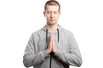 alm praying man the athlete closed his eyes in prayer, his hands folded with his hands together to each other. Dressed in a gray hooded jacket, short haircut. Isolated