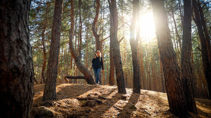 Naklejka na ściany i meble Beautiful young female hiker walking in forest at sunset