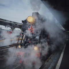 Departure of an old steam train from an uninhabited city railway station.