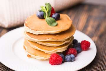 Pancakes with blueberries and raspberry on wooden background. Breakfast and traditional meal.