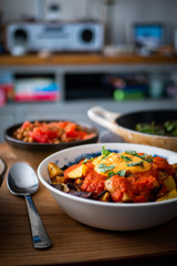 Patatas Bravas in a bowl, surrounded by Padron peppers and fish. Healthy Spanish food taken portrait